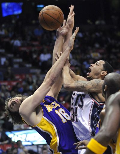 Devin Harris plows into Pau Gasol, but the Lakers’ big man does most of the punishing, scoring 36 points in win over New Jersey. (Associated Press / The Spokesman-Review)