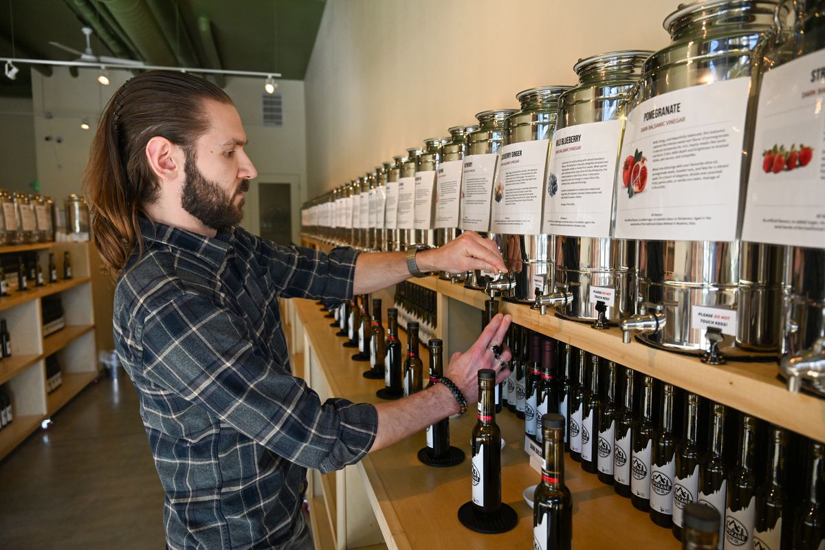 Mitchell Moczulski fills a bottle Oct. 27 in his newly opened shop, Spokane Olive Oil, in the Kendall Yards Neighborhood where he sells a wide variety of fresh olive oils, balsamic vinegars and specialty foods. Moczulski, who credits healthy foods like fresh olive oils with overcoming rheumatoid arthritis, owns the shop with his husband Kyle Rohr. (Jesse Tinsley/THE SPOKESMAN-REVI)