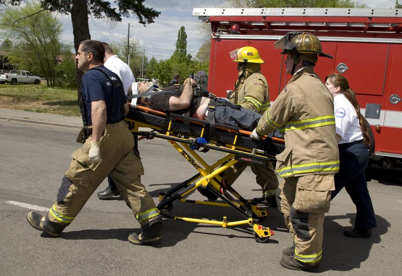 A man working for Hammerhead Demolition Inc. is taken to an awaiting ambulance after Spokane firefighters freed him from under a house that collapsed at 3633 E. Second Ave on Thursday, May 13, 2010. The man was prepping the house to be moved.  (Colin Mulvany / The Spokesman-Review)