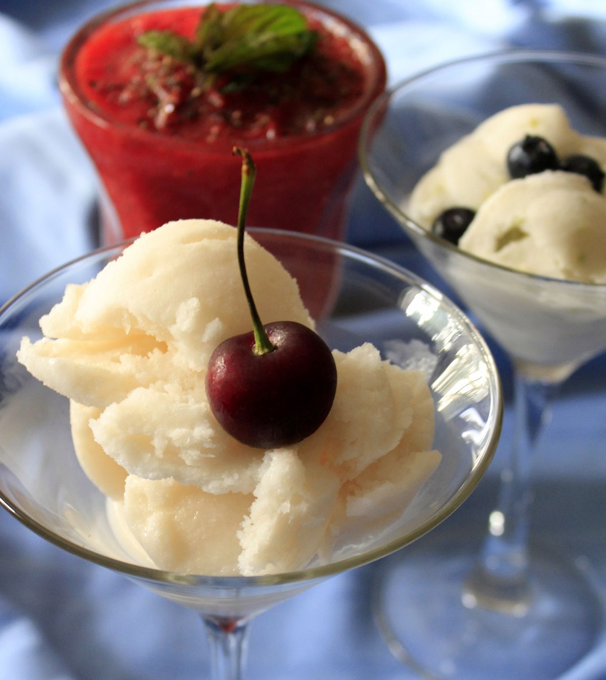 Cool off this Fourth of July weekend with easy-to-make red, white and blue granitas, like this cherry-topped coconut-rum concoction (front) and blueberry-sprinkled coconut-lime or strawberry-black pepper flavors. (Adriana Janovich)