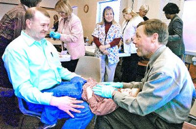 
Connor Duncan, 3, rests on the legs of his father, Scott, left, and Spokane dentist Dale Ruemping on Wednesday  at the Lidgerwood Group Health clinic. A new program integrates dental disease prevention with well-child visits. 
 (Christopher Anderson / The Spokesman-Review)