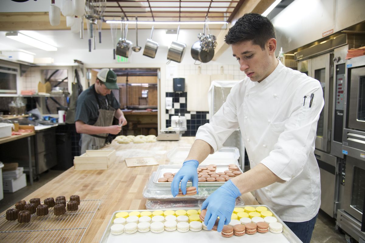 Bakery chef Taylor Siok, right, prepares trays of French macarons at Common Crumb on Tuesday while bread apprentice Liam Dempsey, left, works on loaves of challah bread. The bakery will specialize in breads, pastries, and chocolates. (Jesse Tinsley)