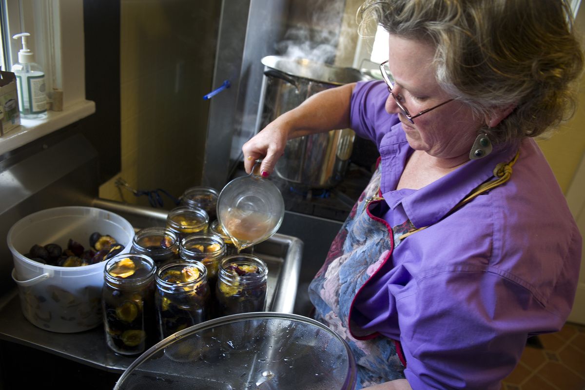 Petunias Marketplace employee Beverly Bailey pours spiced liquid into jars of fresh Italian plums. (Colin Mulvany)