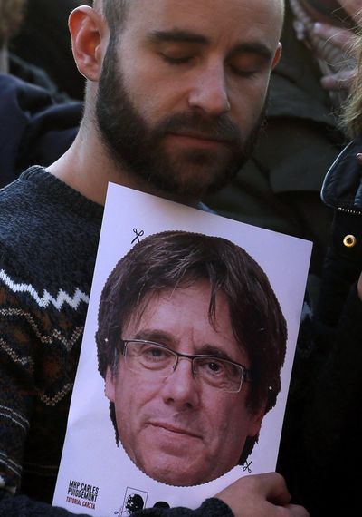 A man holds a mask of Catalonia’s fugitive ex-president Carles Puigdemont during a protest outside of the Parliament of Catalonia in Barcelona, Spain, Tuesday, Jan. 30, 2018. Plans by Catalan separatist lawmakers to re-elect fugitive ex-president Tuesday received a setback when the house speaker postponed the session, saying the planned parliament meeting would not take place until there were guarantees Spanish authorities “won't interfere.” (Manu Fernandez / Associated Press)
