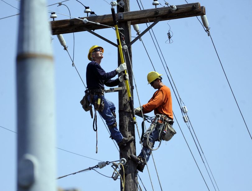 Avista Utilities linemen work on a power pole high above Division St. and Hawthorne Rd. Sunday, Aug. 3, 2014. A wind storm torn down lines and threw thousands into darkness Saturday evening and crews are working to get power restored. (Jesse Tinsley/SR photo)