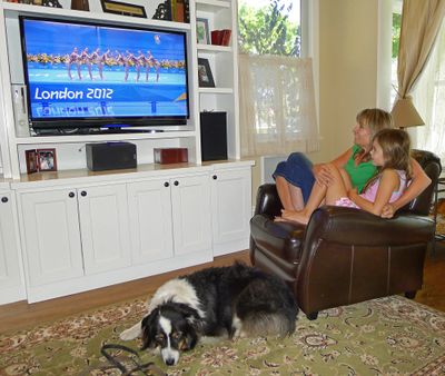 Julie O’Grady watches the 2012 Olympics with her daughter Molly and dog Bosco on Thursday in her home in Palo Alto, Calif. (Associated Press)