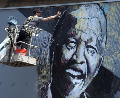 Jessie Pierpoint adds some finishing touches to his image of Nelson Mandela on his billboard project near the corner of Main and Bernard, July 11, 2014, in Spokane, Wash.  Pierpoint conducted a live billboard painting for Global Credit Union's Global Citizen Campaign.  The program supports local emerging artists.  DAN PELLE danp@spokesman.com (Dan Pelle / The Spokesman-Review)