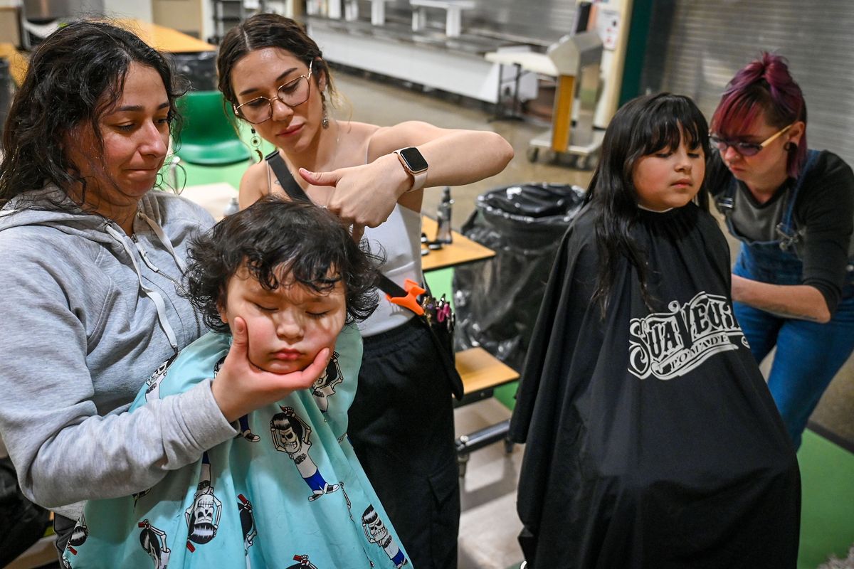Christina Ziegler, left, took her son, Xavier, 2, to get his first haircut by Isabel Russell, of the Man Shop, on Thursday at Holmes Elementary School in Spokane. At right, Lucy Ziegler, 6, a first-grader at Holmes, gets a trim from Jordan Strong. Eight stylists from the Man Shop gave free haircuts to students and their families after Holmes Assistant Principal Darren Cromeenes reached out to the hair business to see if they would donate their services.  (DAN PELLE/THE SPOKESMAN-REVIEW)