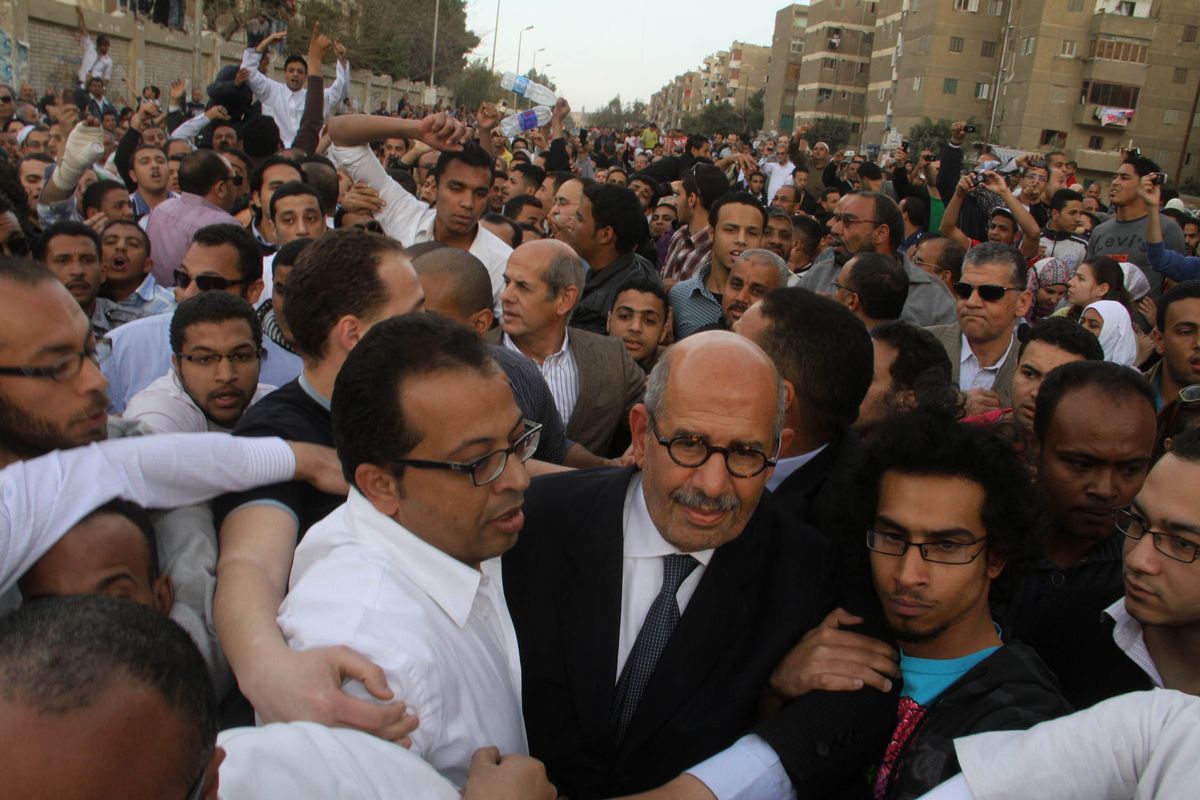 Supporters of Egyptian reform campaigner Mohamed ElBaradei, front center, try to protect him as angry protesters shout slogans as he arrives to cast his vote in Cairo’s Mokkatam district on Saturday. (Associated Press)