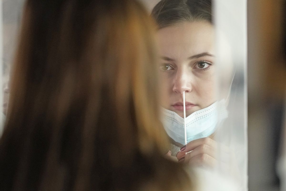 FILE — In this Nov. 18, 2020, file photo, University of Utah student Abigail Shull takes a rapid COVID-19 test in Salt Lake City. As coronavirus cases are surging around the U.S., some colleges and universities are rethinking some of their plans for next semester. (Rick Bowmer)