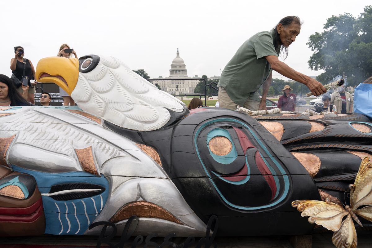 A person blesses a totem pole during delivery ceremony by tribal leaders and Indigenous activists, on Capitol Hill in Washington, Thursday, July 29, 2021.  (Jose Luis Magana/Associated Press)