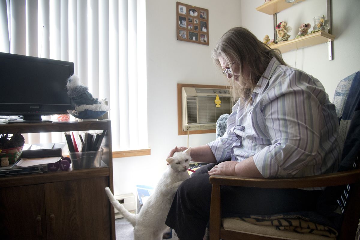 Debra Henderson pets her cat, Jaydee, in her small apartment in Spokane Valley. She