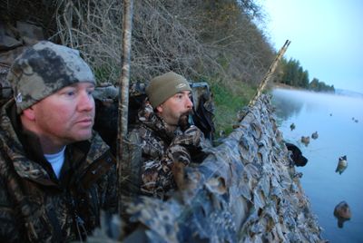 Kent Contreras calls in a flight of ducks while hunting out of his boat blind with Allen Riggs on the Pend Oreille River during the opening of Washington’s waterfowl season. Tank, Contreras’ black Lab, looks on from his retrieving station at the end of the boat.  (Rich Landers / The Spokesman-Review)