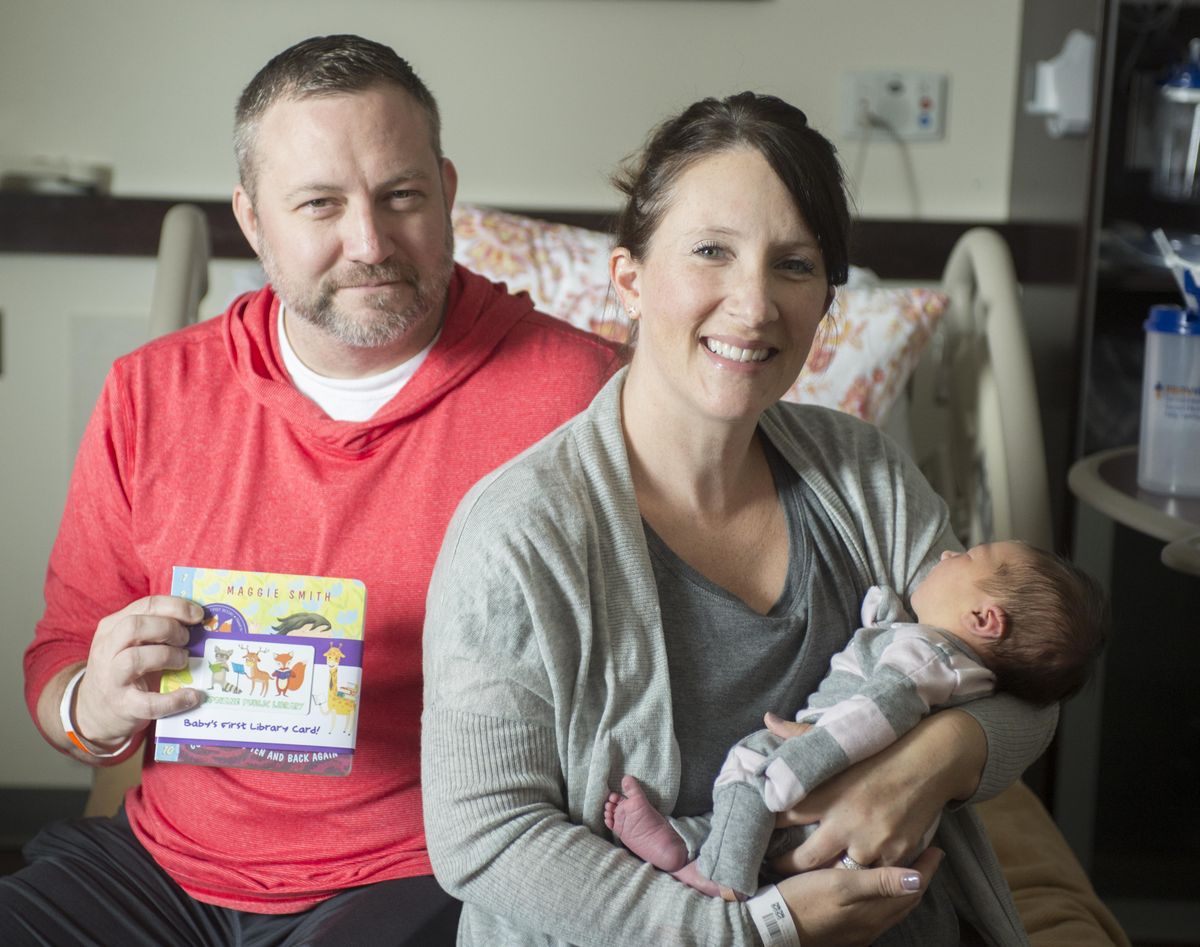 Terry and Amy Donovan, with their baby, Etta, show off the board book and new library card presented to them shortly after the birth of their second child at Providence Holy Family recently. The couple, seen shortly before leaving the hospital Tuesday, Aug. 29, 2017, are one of the first families to benefit from  the Spokane Public Library’s Books for Babies program. (Jesse Tinsley / The Spokesman-Review)