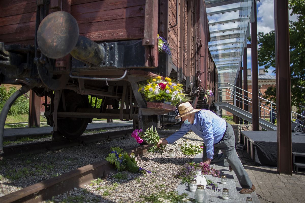 A man lays flowers on rusty railway tracks near old wagons at the Naujoji Vilnia railway station in Vilnius, Lithuania, Monday.  (Mindaugas Kulbis)