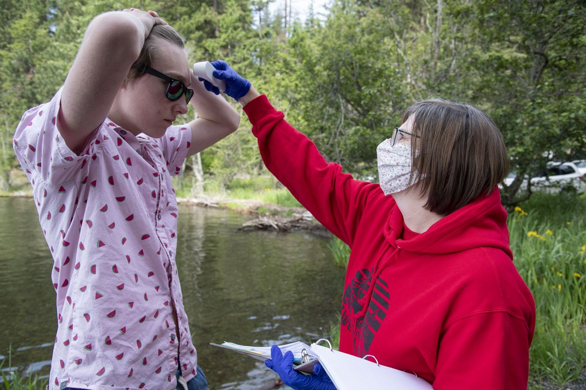 Poppy White, right, director of camping and program services for Camp Fire Inland Northwest, checks the temperature of Paden Buenzli, 15, before boarding the boat to Camp Sweyolakan on Lake Coeur d’Alene on June 19.  (Jesse Tinsley/The Spokesman-Review)