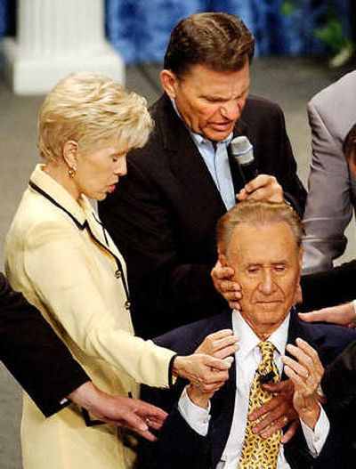 
At left, televangelist Gloria Copeland and Kenneth Copeland lay hands on Oral Roberts, 85, in this 2003 file photo.
 (The Spokesman-Review)