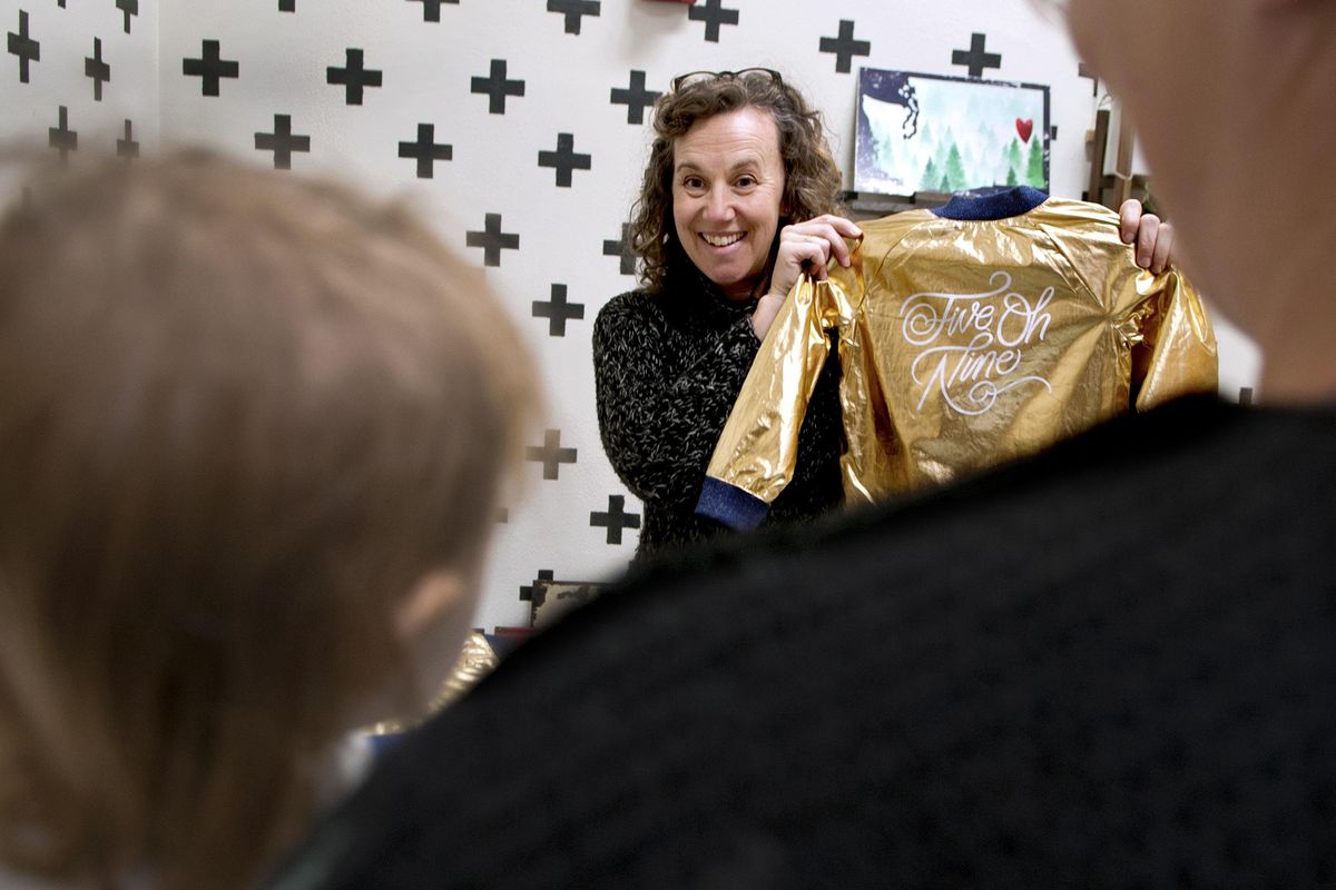 Kelly Baker, manager of Pop Up Shop, shows a jacket to customers at the store in Spokane on Wednesday, Nov. 15, 2017. (Kathy Plonka / The Spokesman-Review)