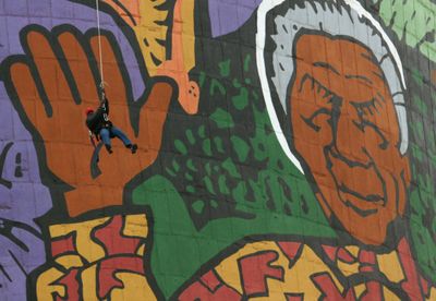 A rappeller swings between Orlando Power Station towers against a portrait of Nelson Mandela in Soweto, South Africa, on Saturday. (Associated Press / The Spokesman-Review)