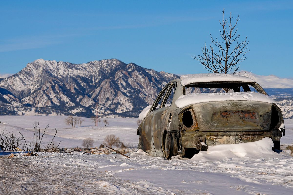 Snow covers the burned remains of a car Sunday after wildfires ravaged the area around Superior, Colo.  (Jack Dempsey)