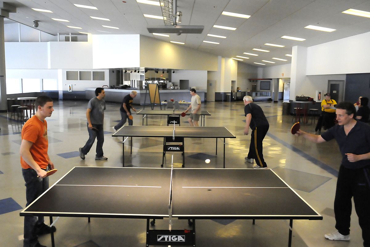 Julian Helmke, left,  John Trevethan,  right, and other players gather around their tables as they compete in the table tennis tournament Saturday at Greyhound Park and Event Center in Post Falls. (Jesse Tinsley)