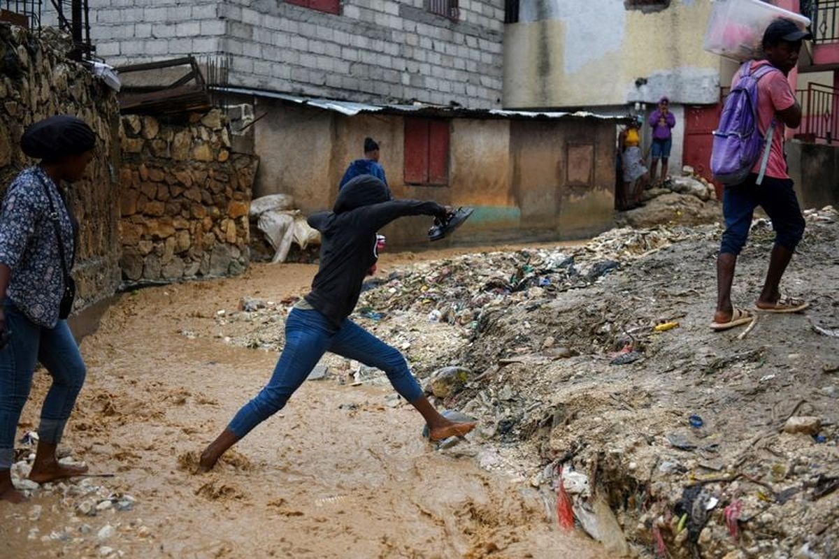 People cross a flooded street after heavy rains caused by the outer bands of Hurricane Melissa flooded some areas, in Port-au-Prince, Haiti, October 29, 2025. REUTERS/Johnson Sabin (Johnson Sabin)