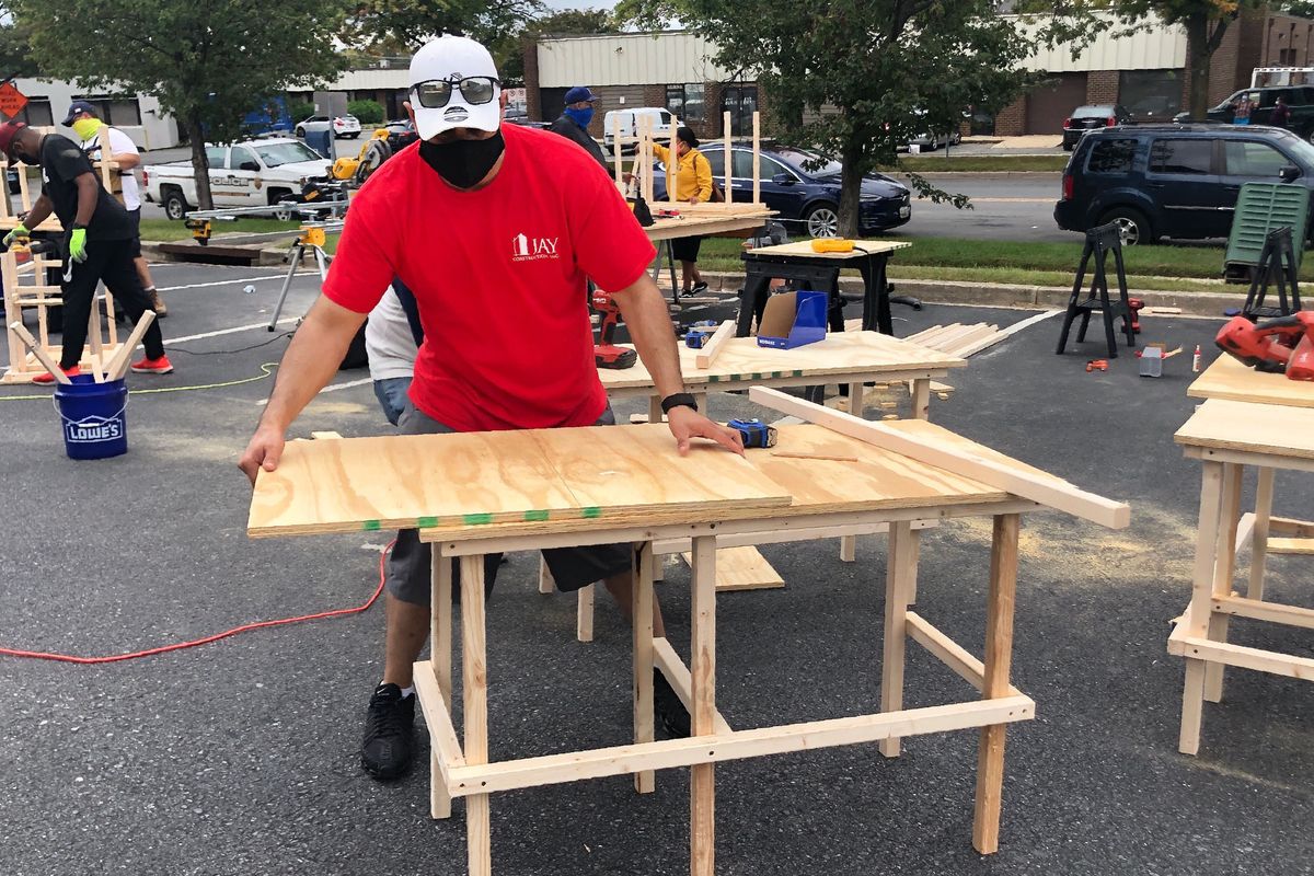 In this photo provided by Jessica Berrellez, her husband, Al Berrellez, builds a desk in Gaithersburg, Md., on Friday, Sept. 25, 2020. The couple, with the help of some 60 community volunteers, have built and donated over 100 desks so far to students and families in need.  (Jessica Berrellez)