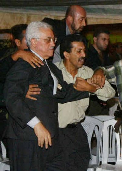 
Bodyguards take away Mahmoud Abbas after gunfire erupted at the tent set up for mourners to gather in memory of Yasser Arafat in Gaza City on Sunday. 
 (Associated Press / The Spokesman-Review)