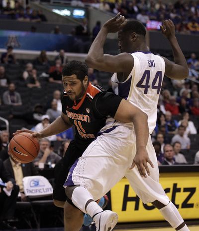 Oregon State's Joe Burton, left, drives past Washington's Darnell Gant during the second half of an NCAA college basketball game at the Pac-12 conference championship in Los Angeles Thursday. Oregon State won 86-84. (Associated Press)