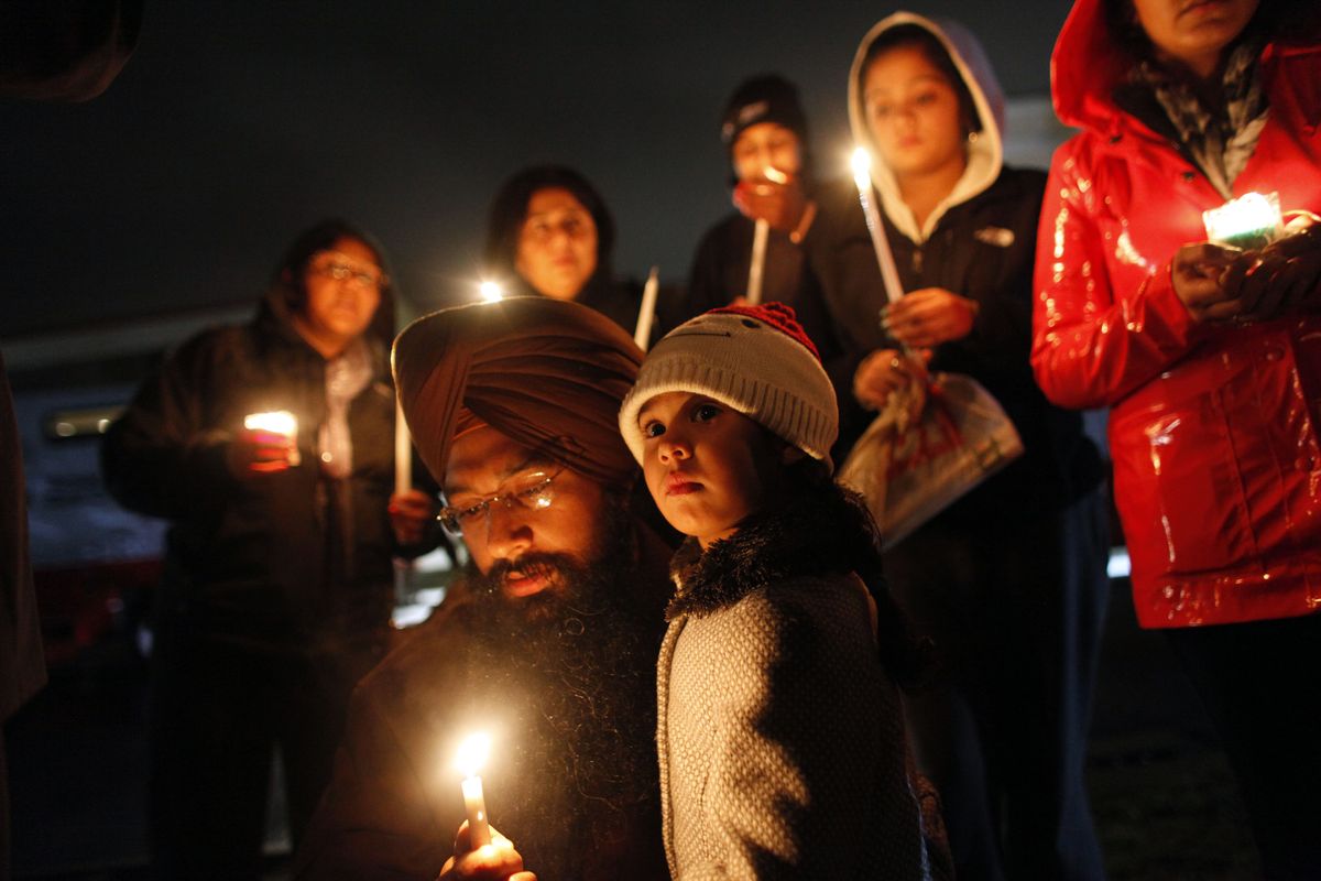 Eknoor Kaur, 3, stands with her father, Guramril Singh, during a candlelight vigil before an interfaith vigil with President Barack Obama on Sunday in Newtown, Conn. (Associated Press)