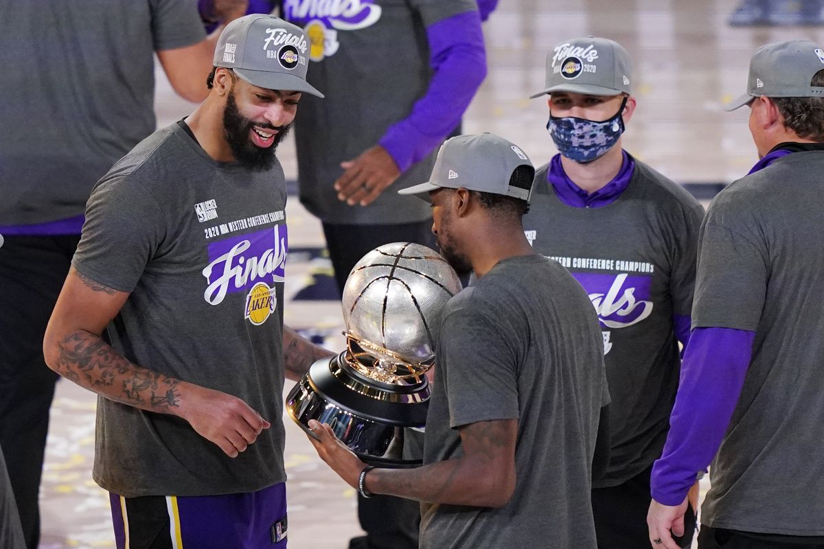 Los Angeles Lakers’ Anthony Davis, left, looks at their trophy after beating the Denver Nuggets in an NBA conference final playoff basketball game Saturday, Sept. 26, 2020, in Lake Buena Vista, Fla. The Lakers won 117-107 to win the series 4-1.  (Mark J. Terrill)