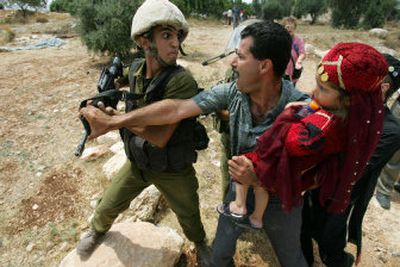 
A Palestinian man holding his child scuffles with an Israeli officer Friday during a wedding ceremony, as part of a protest against Israel's separation barrier, near the West Bank town of Ramallah. 
 (The Spokesman-Review)