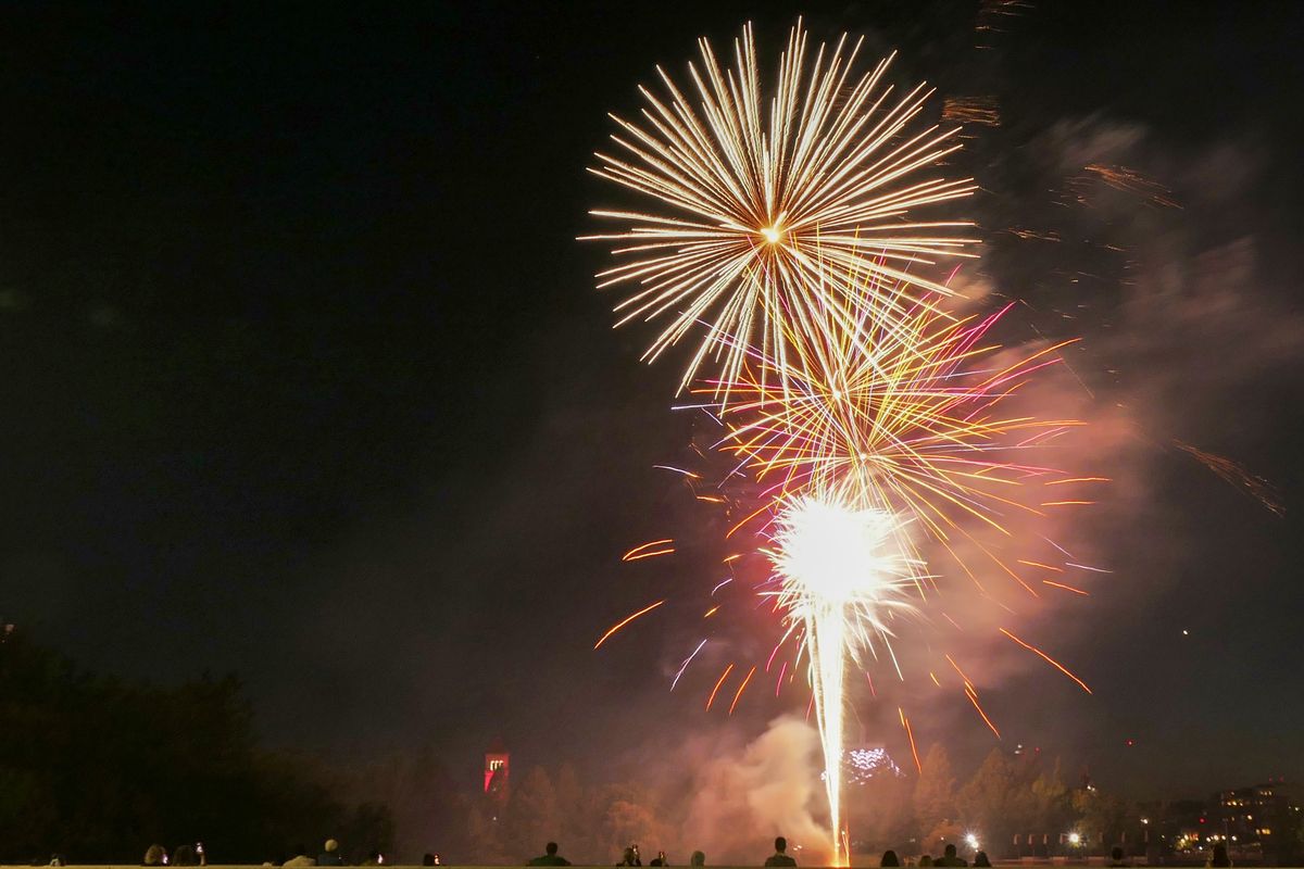 Spectators watch from the Division Street Bridge as fireworks light up the sky over Spokane