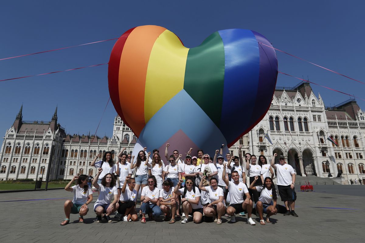 Activists pose for a photo after erecting a large rainbow-colored heart in front of the country