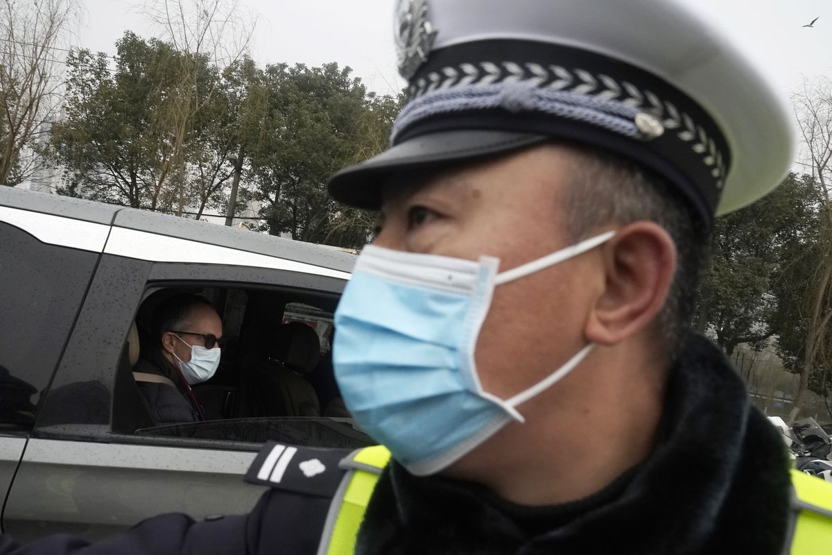Peter Ben Embarek of the World Health Organization team passes by a Chinese police officer as he leaves in a convoy from the Baishazhou wholesale market on the third day of field visit in Wuhan in central China’s Hubei province on Sunday, Jan. 31, 2021.  (Ng Han Guan)