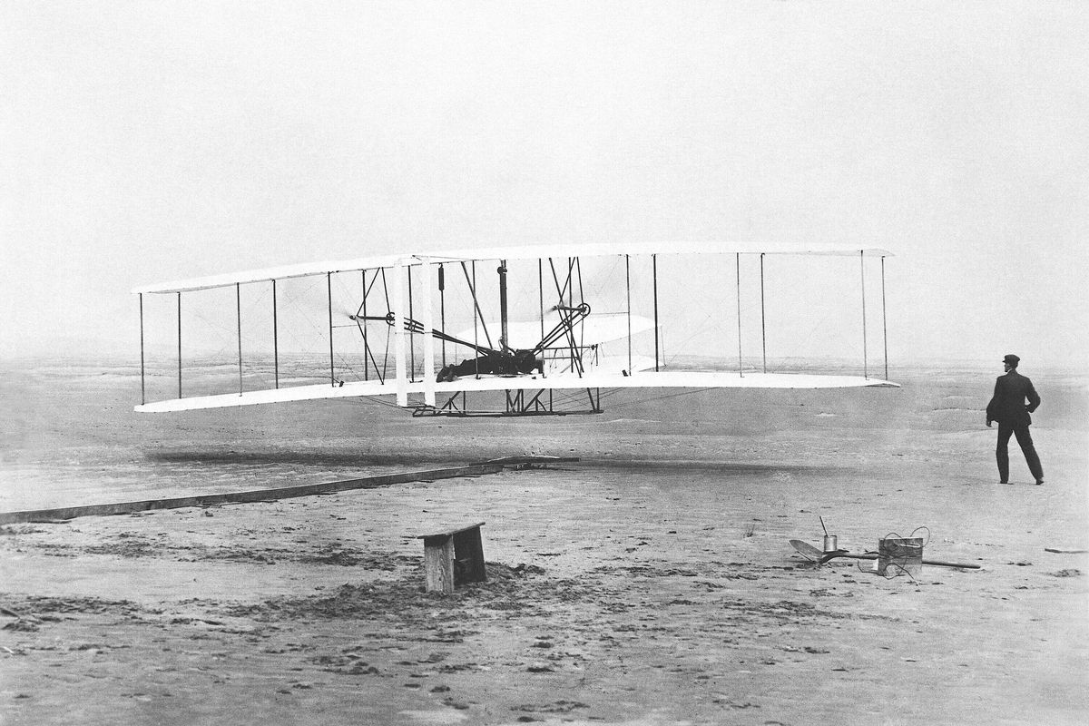 FILE - Orville Wright is at the controls of the "Wright Flyer" as his brother Wilbur Wright, right, looks on during the plane's first flight at Kitty Hawk, N.C., on Dec. 17, 1903. A backwards image of the Wright Flyer that appeared on the initial version of Ohio’s new license plate was added to the design early and never changed or questioned throughout the approval process, according to public records obtained by The Associated Press. The error was fixed only after the public unveiling in October drew attention to it.  (John T. Daniels)