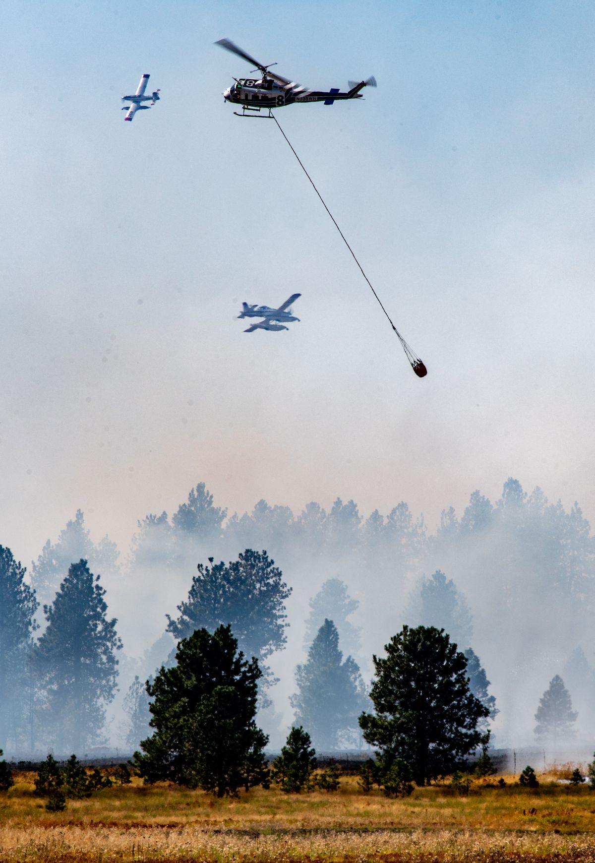 Firefighting aircraft and helicopters drop water to help contain a fast-moving brush and timber fire near Medical Lake, Thurs. Aug. 27, 2020. (Colin Mulvany/THE SPOKESMAN-REVIEW)