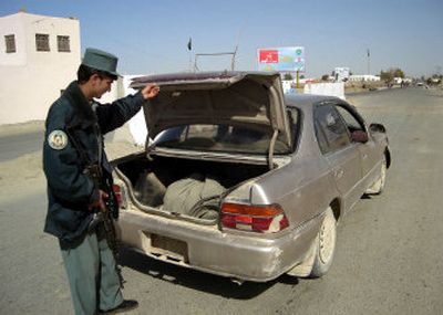 
An Afghan police officer checks the trunk of a car  near Lashkar Gah, the provincial capital of Helmand province, on Tuesday. 
 (Associated Press / The Spokesman-Review)