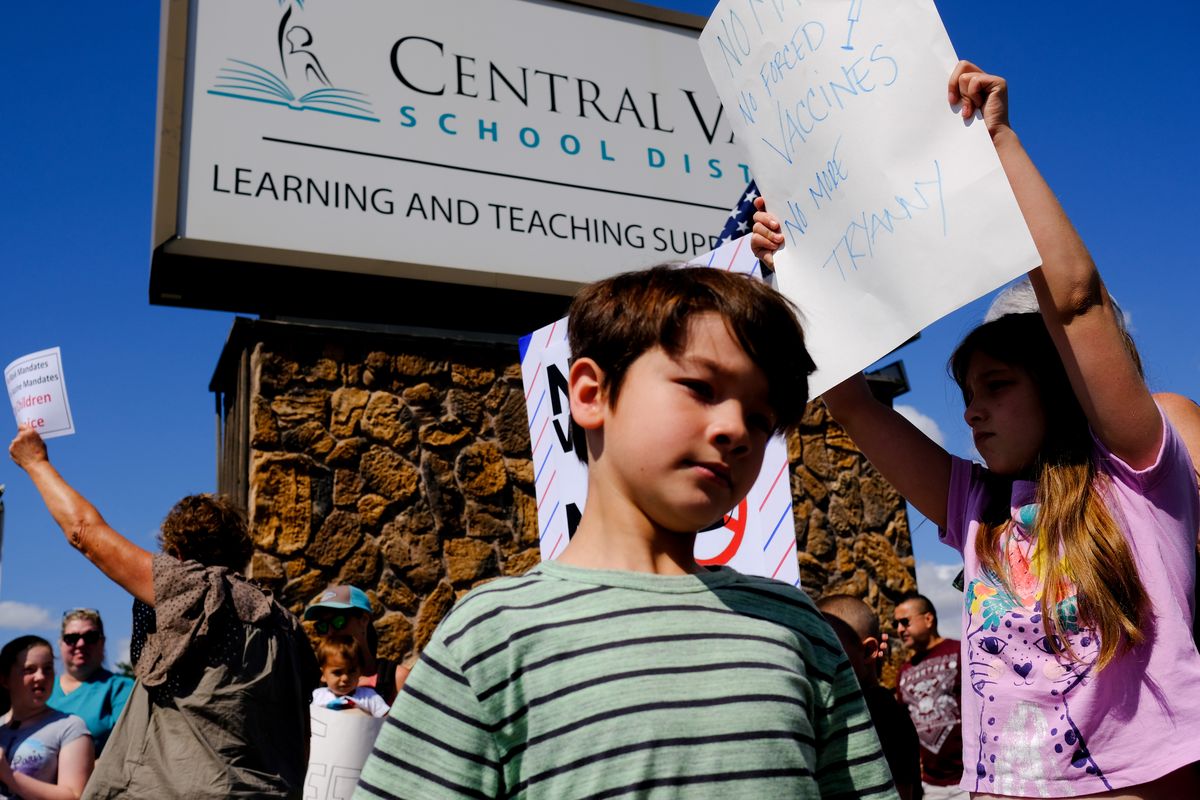 Lauren, 9, right, whose mother asked that her last name not be used, holds a sign denouncing mask mandates as she joins other children and their parents in protesting COVID-19 regulations on Aug. 18 at the Central Valley School District’s offices in Spokane Valley.  (Tyler Tjomsland/The Spokesman-Review)