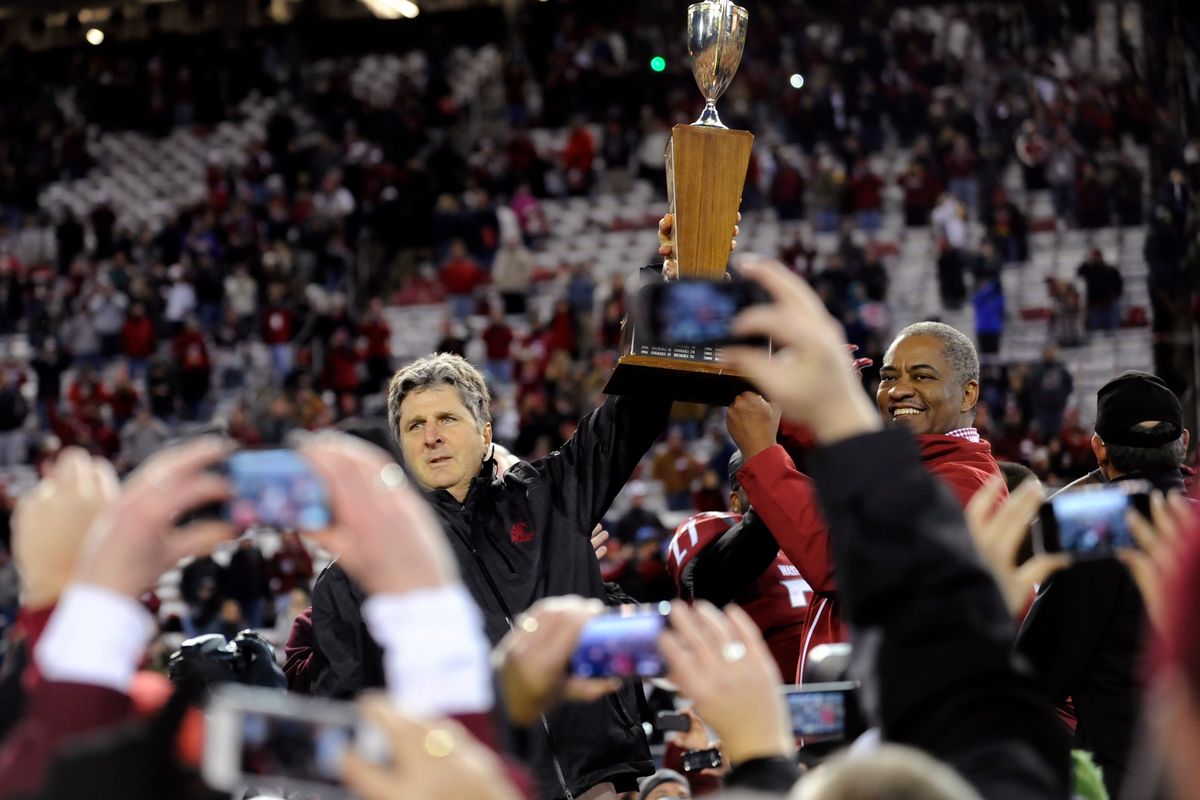 Washington State head coach Mike Leach and President Elson S. Floyd hoist the Apple Cup trophy before fans and players after WSU defeated Washington 31-28 in overtime on Nov. 23, 2012, in Pullman.  (TYLER TJOMSLAND)