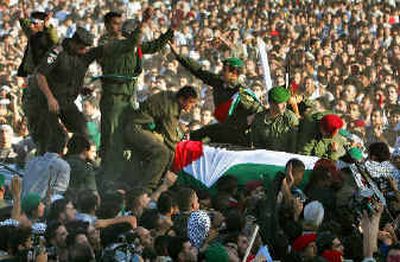 
The coffin of Yasser Arafat is moved through a crowd of Palestinian mourners before being lowered into the grave in Ramallah. 
 (Associated Press / The Spokesman-Review)