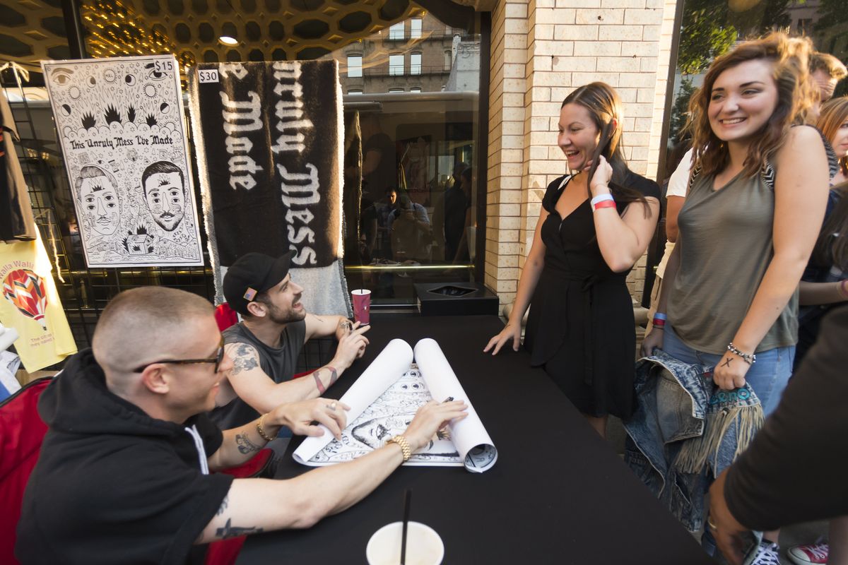Macklemore (left) and Ryan Lewis sign a poster for Jessica Randock (in back) and a jean jacket for Danielle Hansen before the hip hop duo