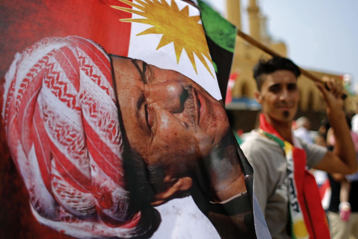 In this Sunday, Sept. 17, 2017 file photo, a man holds a Kurdish flag with a picture of the president of Iraqs Kurdish region Masoud Barzani during a gathering to support a Kurdish independence referendum in Iraq, at Martyrs Square in Downtown Beirut, Lebanon. Speaking at a press conference in Irbil, Iraq, Barzani said Sunday, Sept. 24, 2017, that the controversial vote on independence will go ahead as planned. Barzani said that while the vote will be the first step in a long process to negotiate independence, the regions partnership with the Iraqi central government in Baghdad is over. (Hassan Ammar / Associated Press)