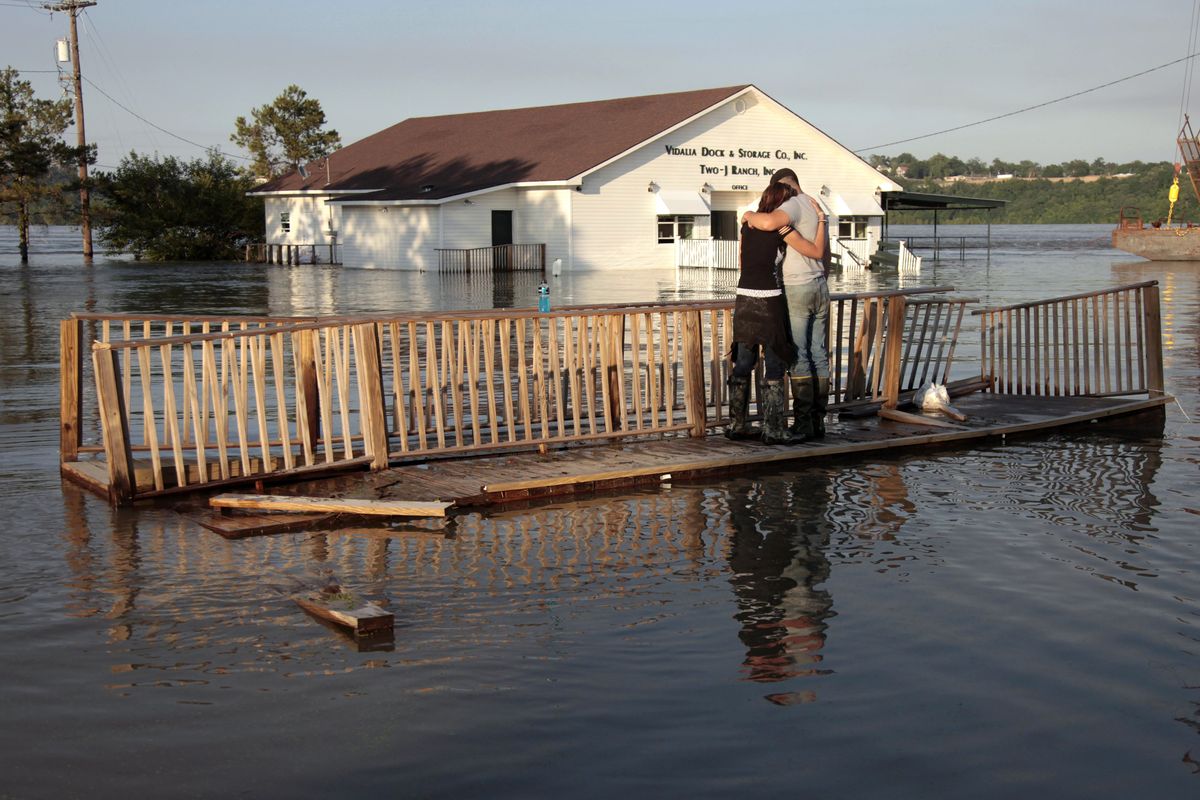 Lauren Lucas, left, is comforted by her husband, David Lucas, as they stand on a broken pier and watch her mother