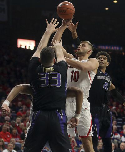Arizona forward Ryan Luther shoots while defended by Washington forward Sam Timmins and guard Matisse Thybulle in the first half Thursday in Tucson, Ariz. (Mamta Popat / AP)