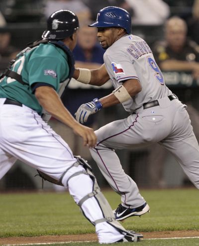 M’s catcher Miguel Olivo, left, tags Rangers' Endy Chavez after Chavez was caught in a rundown. (Associated Press)