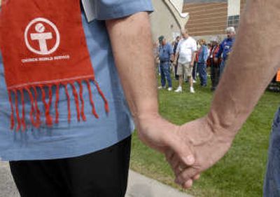 Joseph Urlacher, from the Interfaith Council, Baha'i Faith, holds the hand of Rev. Rick Merlin, of the Presbyterian Church, as participants prayed for hungry and destitute people around the world before the CROP Hunger Walk on Sunday.
(J. Bart Rayniak / The Spokesman-Review)