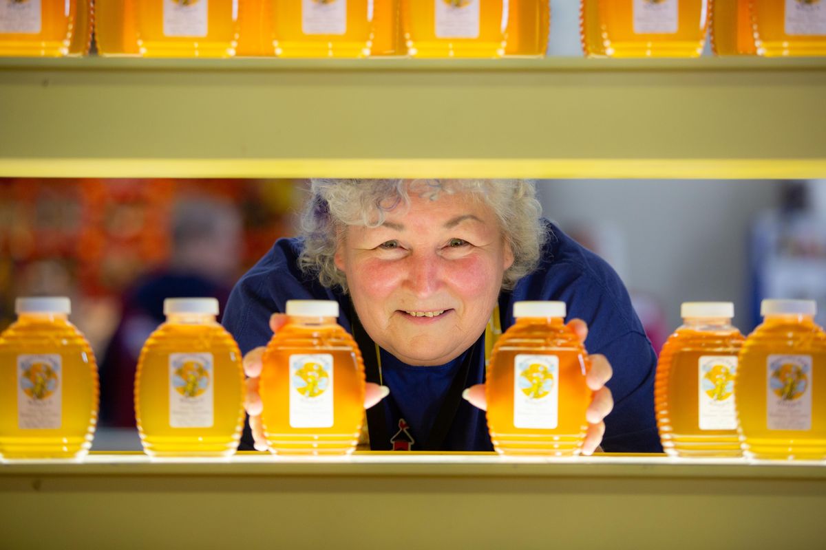 Pat Ayers, who has practiced beekeeping for four years, poses with honey at the Inland Empire Beekeepers Association booth at the Spokane County Interstate Fair on Sept. 13, 2018. Ayers is working on the third level of beekeeping certification as a journeyman, the step before becoming a master beekeeper. (Libby Kamrowski / The Spokesman-Review)