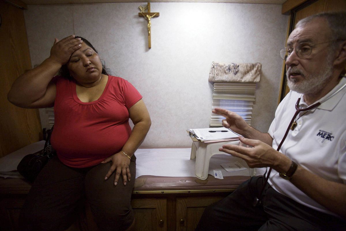 Mission of Mercy’s Dr. Mike Sullivan asks translator Maria-Teresa D’Orazio to translate his instructions to patient Lorena Corilla, 34, during an open clinic at the  Church of the Brethren on Aug. 24 in Frederick, Md. McClatchy-Tribune photos (McClatchy-Tribune photos / The Spokesman-Review)