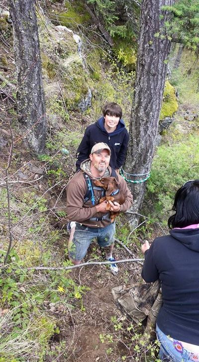 Rob Reed of Spirit Lake holds Daisy, Tom McTevia’s dog that was found Saturday near the site where McTevia died when his ATV rolled off a cliff. Reed’s son, Logan, 15, looks on. (Tonya Reed Facebook)